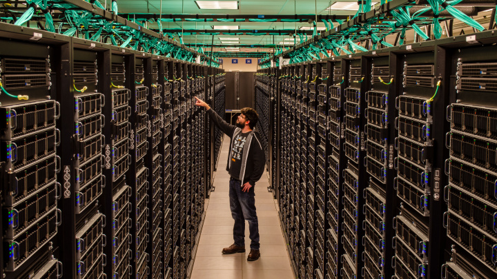 Man standing in aisles of supercomputer data center.