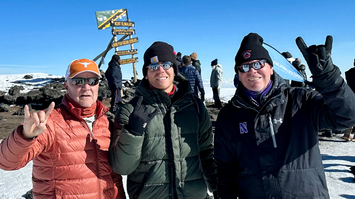 Three climbers celebrate atop Mount Kilimanjaro. 
