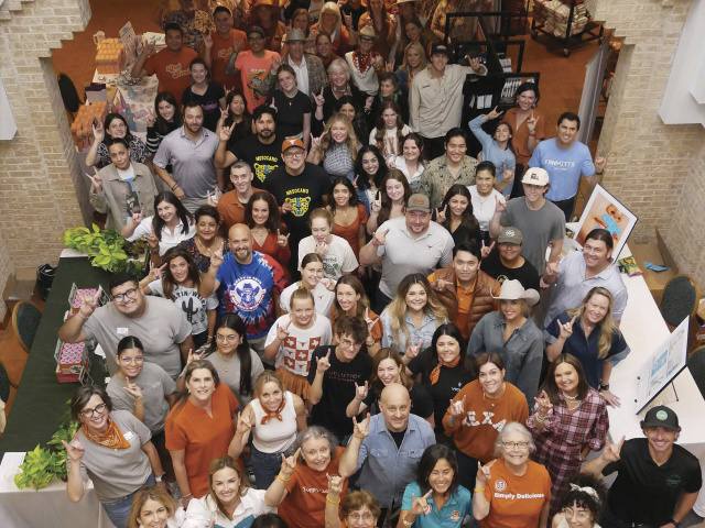 Longhorn Market vendors pose with their "hook em horns" up.
