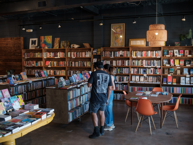Two people look at shelves in a dim and cozy room lined with shelves.