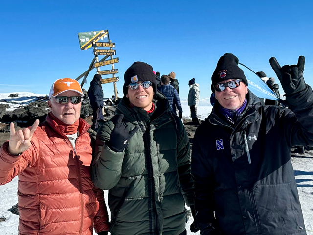 Three climbers celebrate atop Mount Kilimanjaro. 