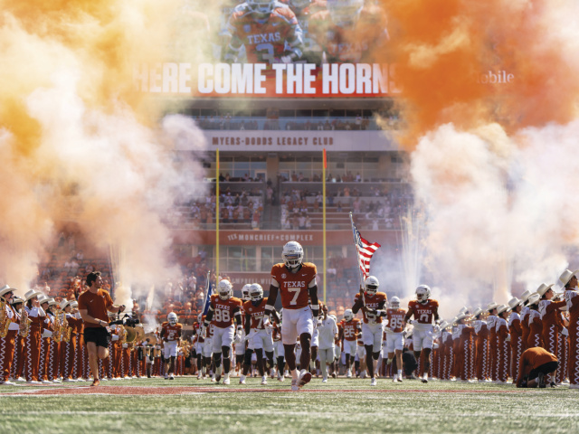 The Longhorn football team runs onto the field. 