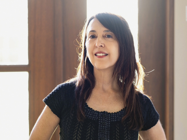 A woman stands backlit by a window.