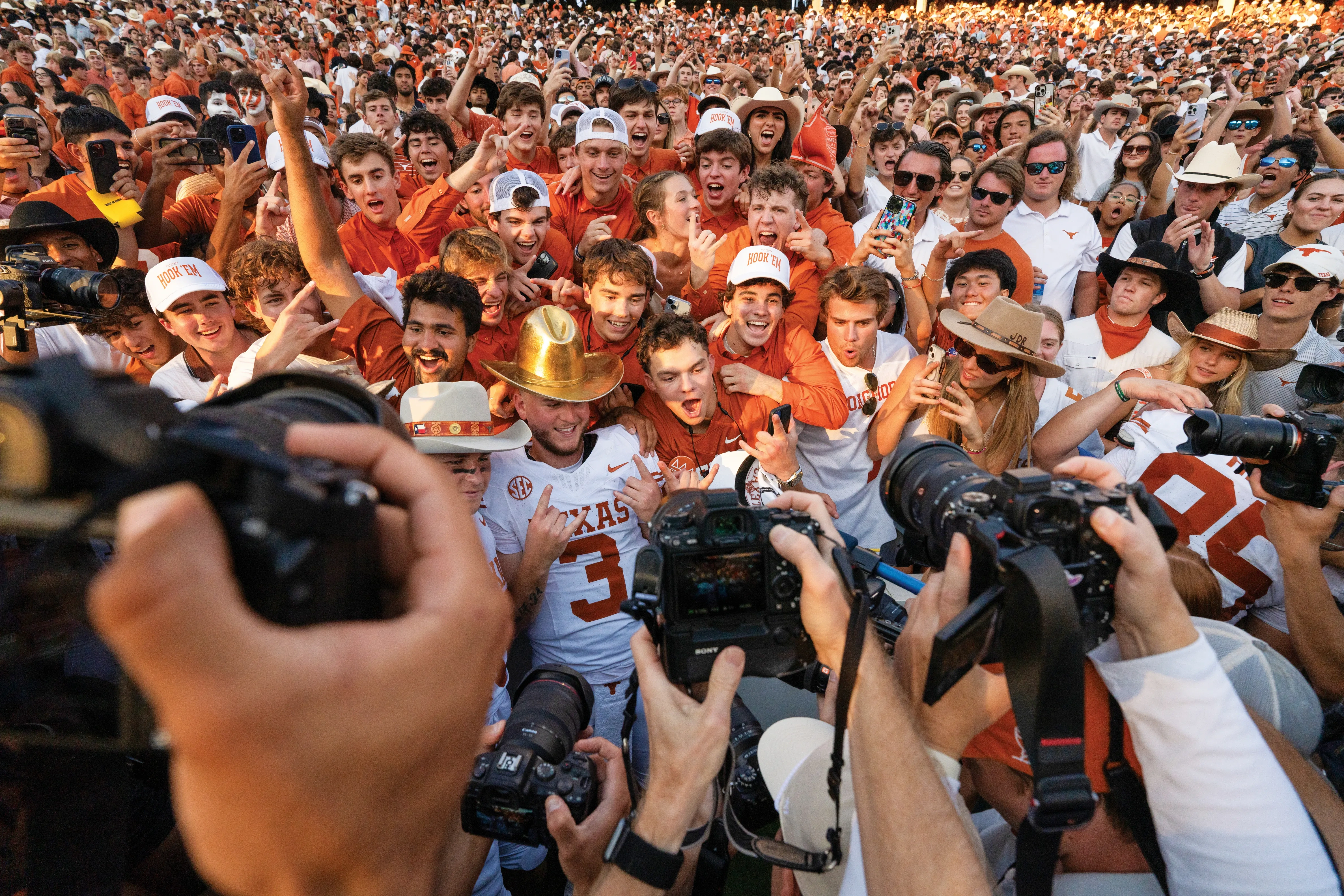 Quinn Ewers in a golden football helmet celebrates in a mob of fans.