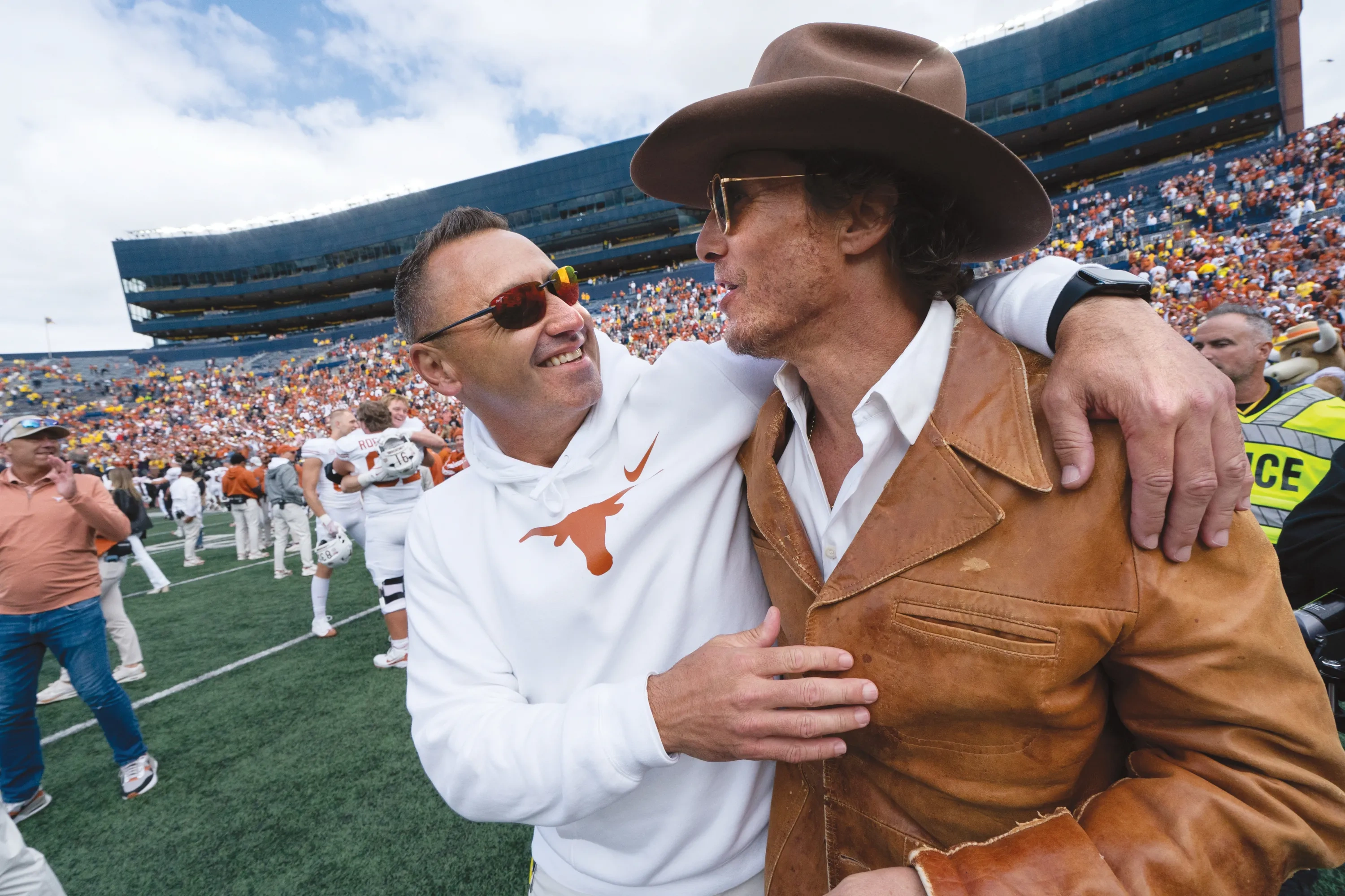 Coach Steve Sarkisian embraces Matthew McConaughey, who wears a cowboy hat.