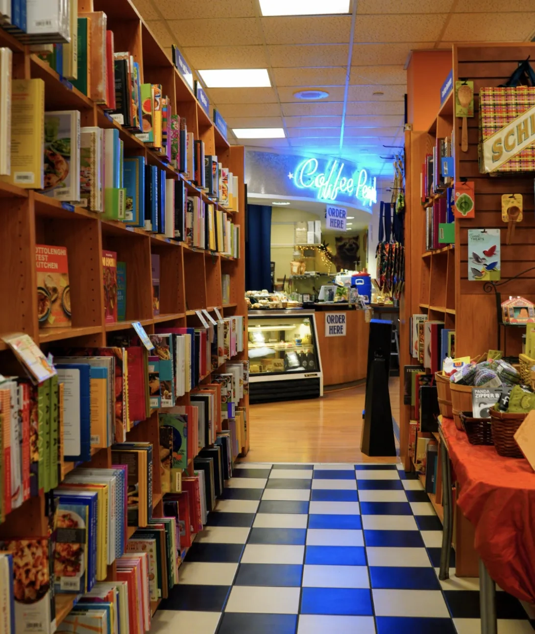 A view between shelves of a neon blue sign for "CoffeePeople" cafe.