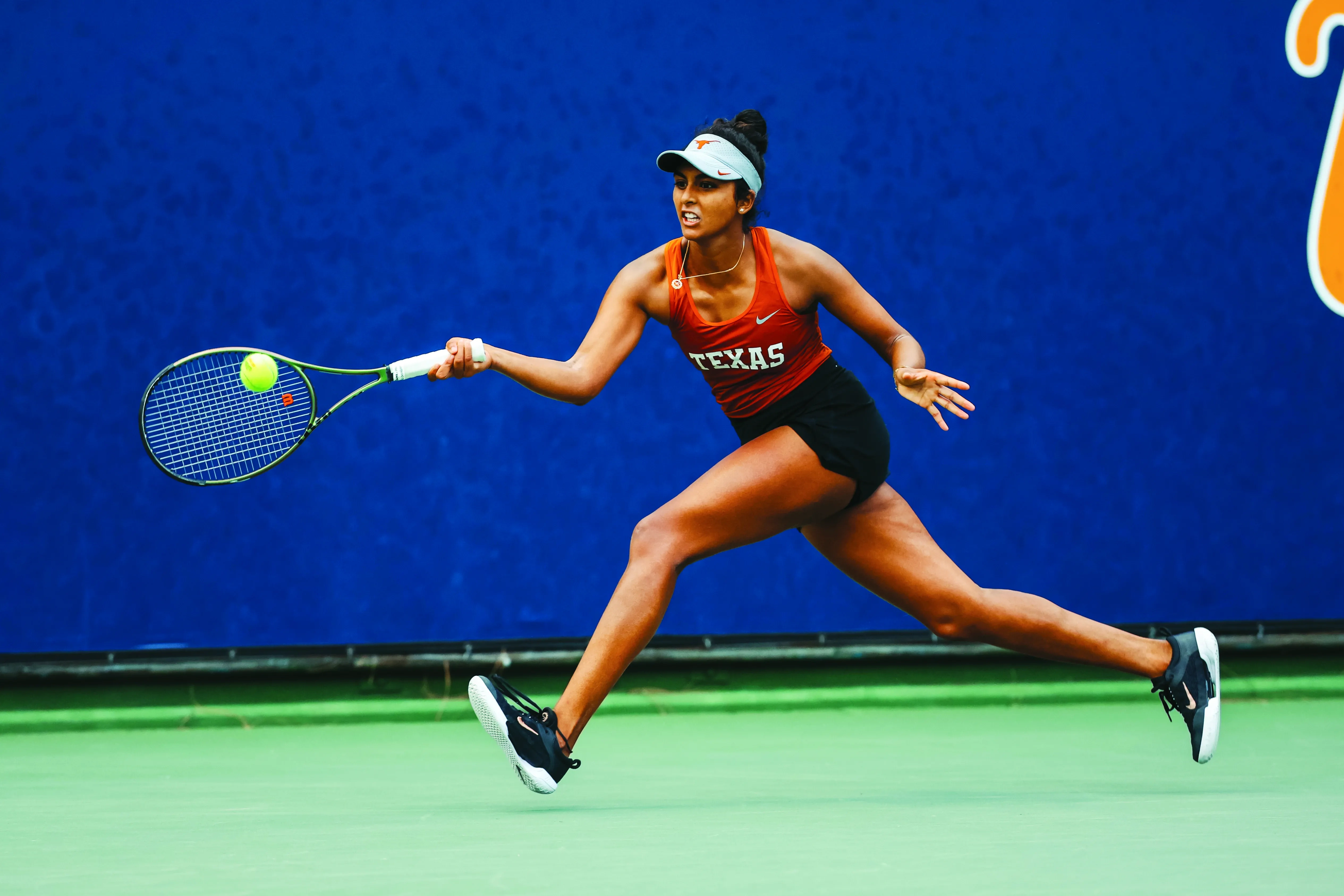 Malaika Rapolou, former Longhorn tennis player, hits tennis ball.