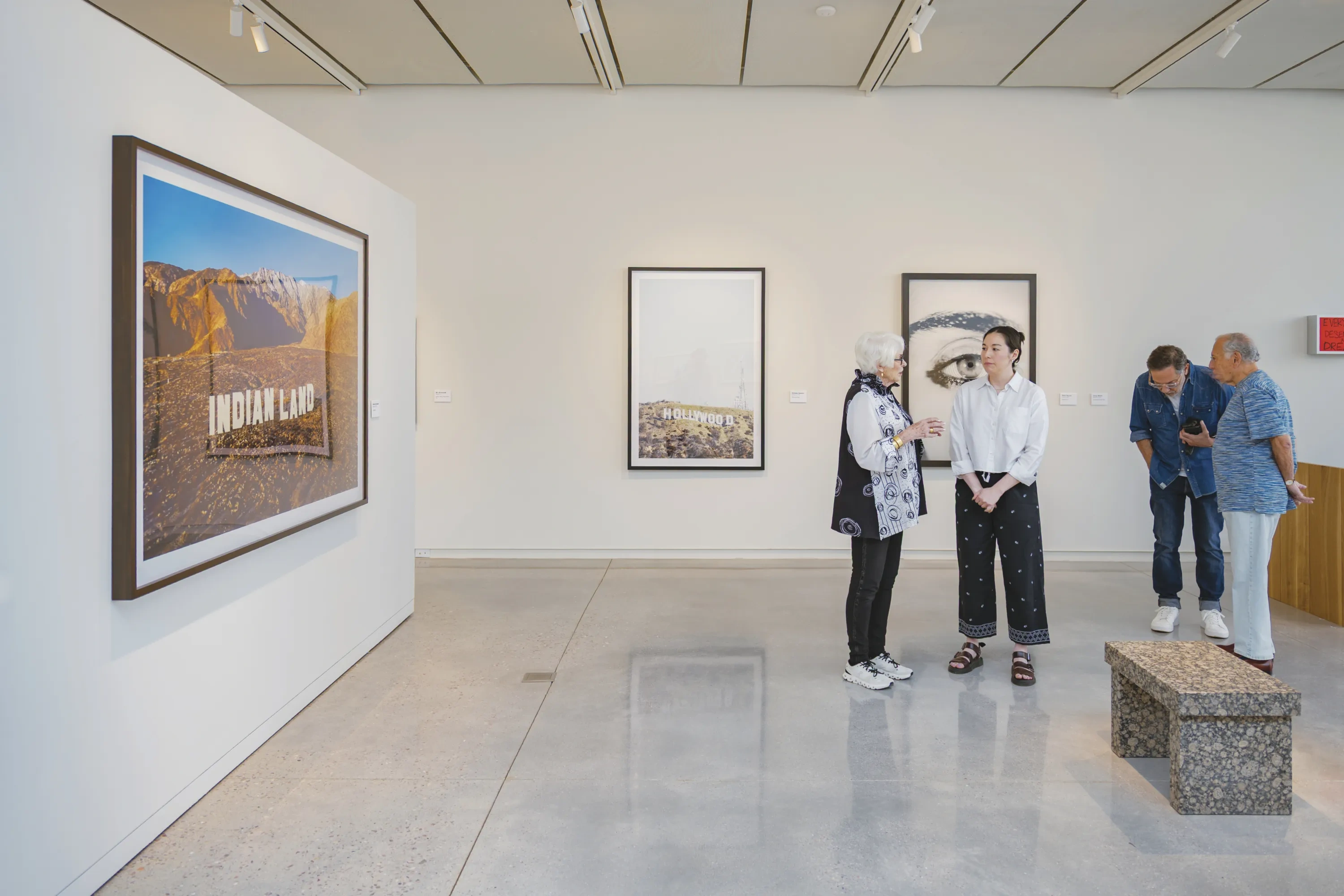 Four people converse in two pairs in an art gallery.