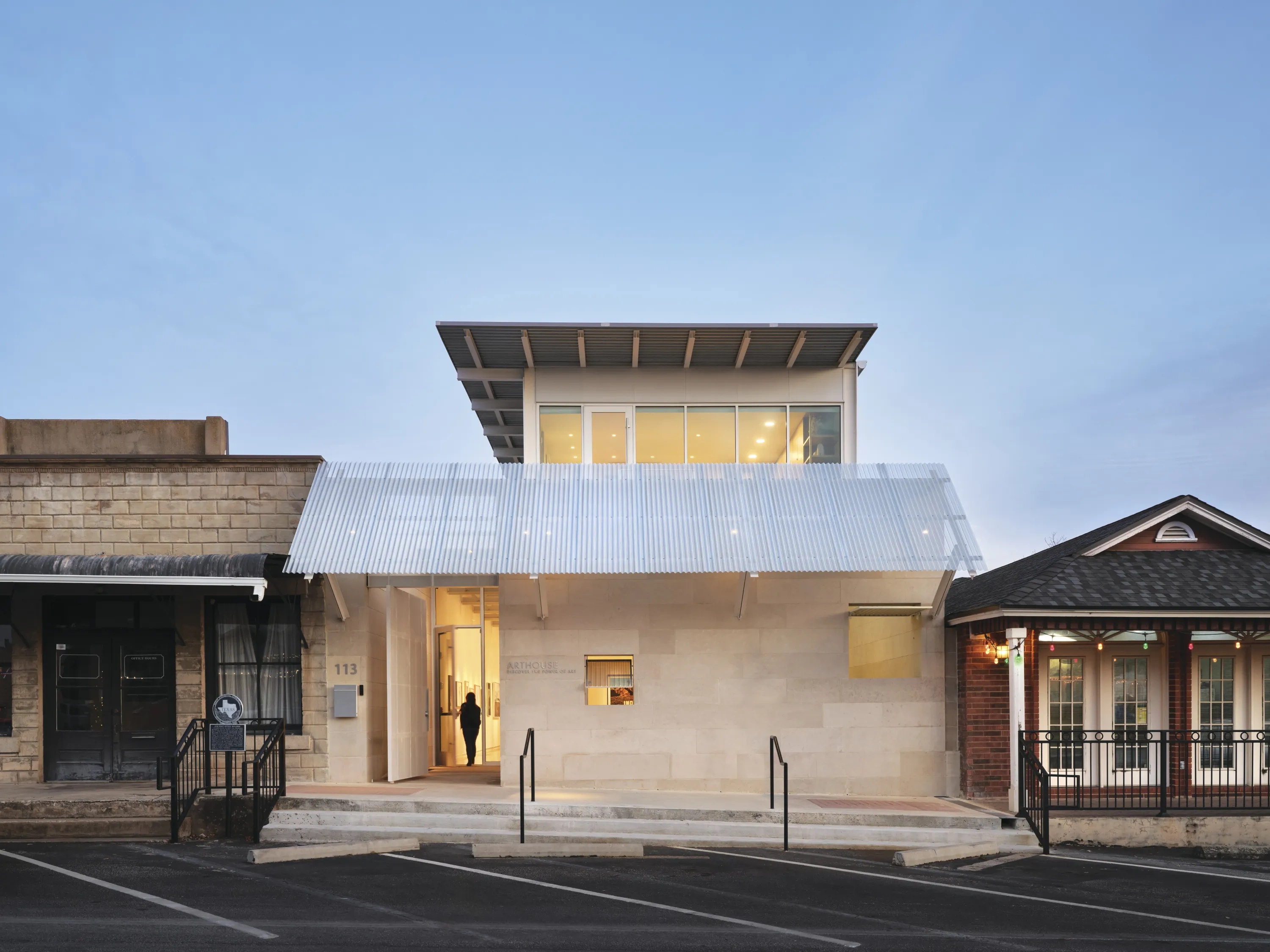 A beautiful modern building sits within the classic architecture of Marble Falls' main street at dusk.