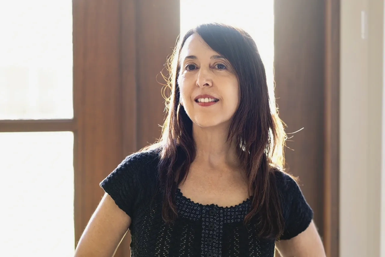 A woman stands backlit by a window.