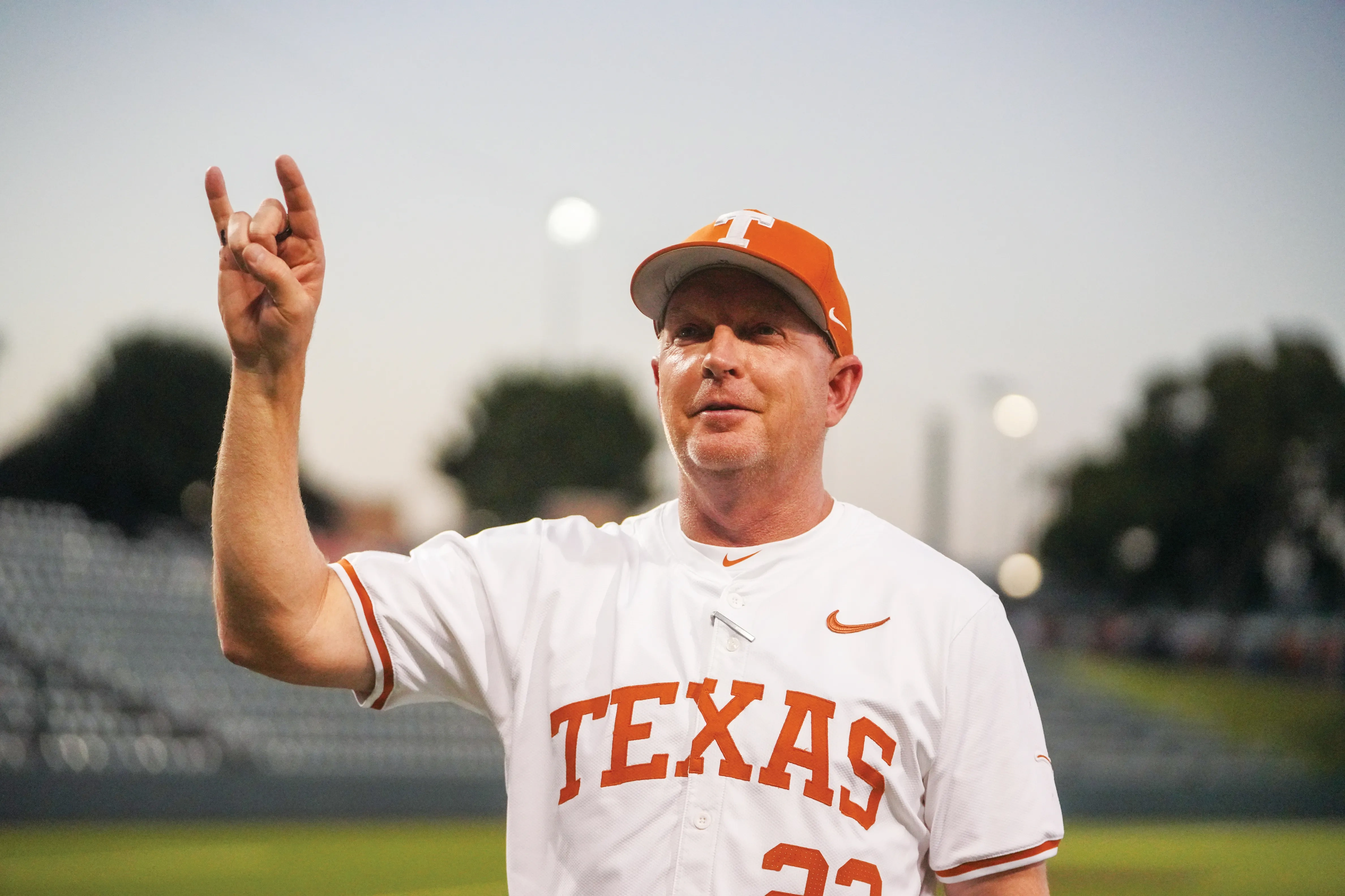 Coach Schlossnagle using the Hook 'Em Horns sign at the UFCU Disch-Falk Field