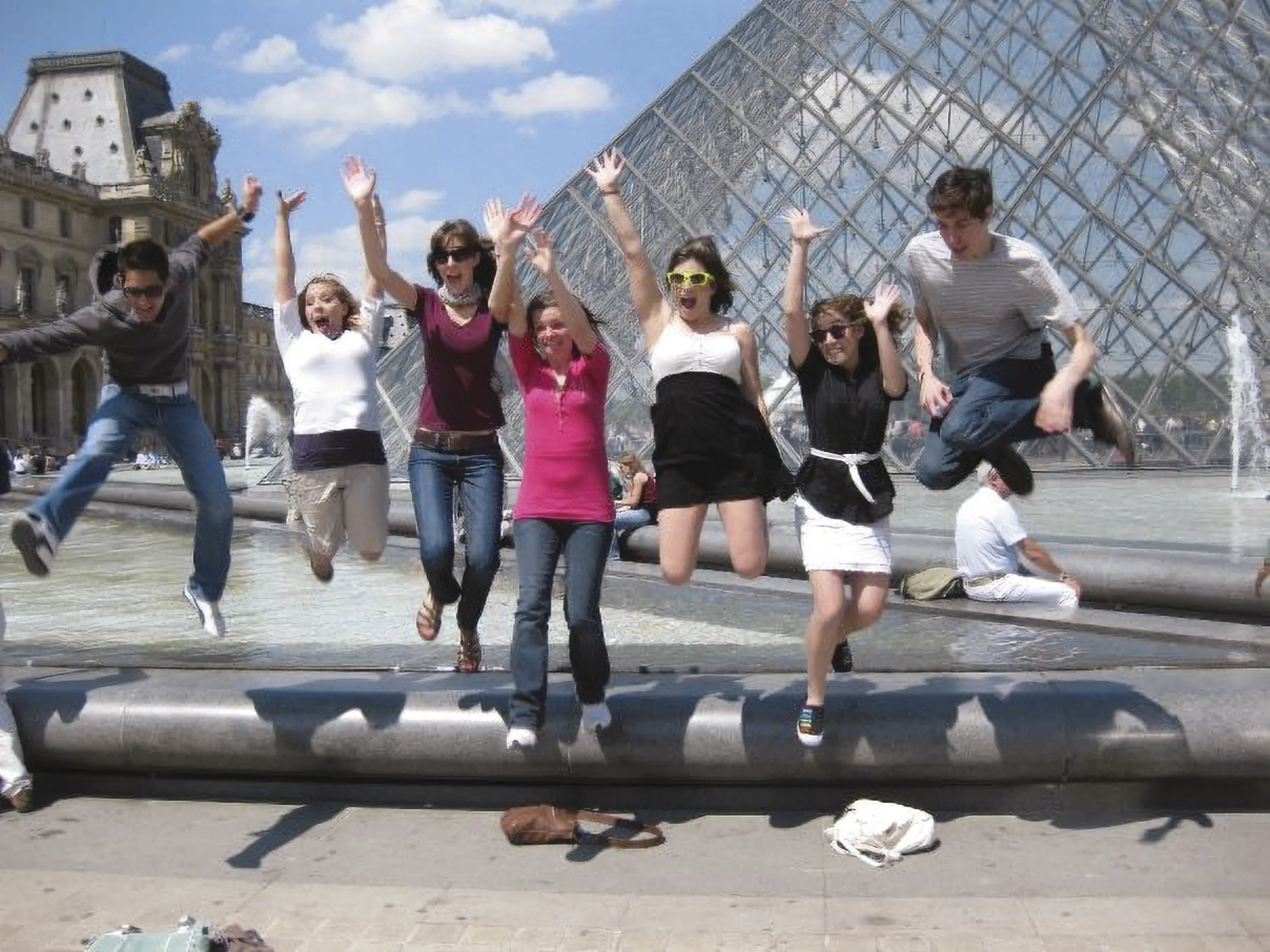 Students jump in front of the Louvre