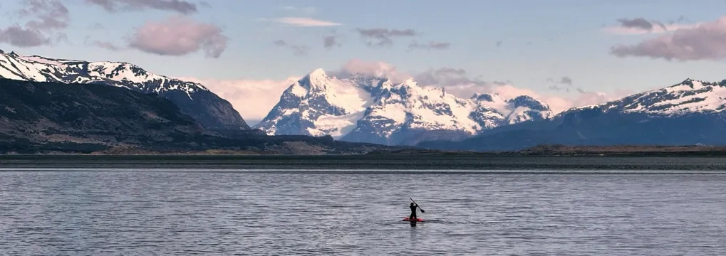 Someone canoes on a lake in Chile. There are mountains in the background.