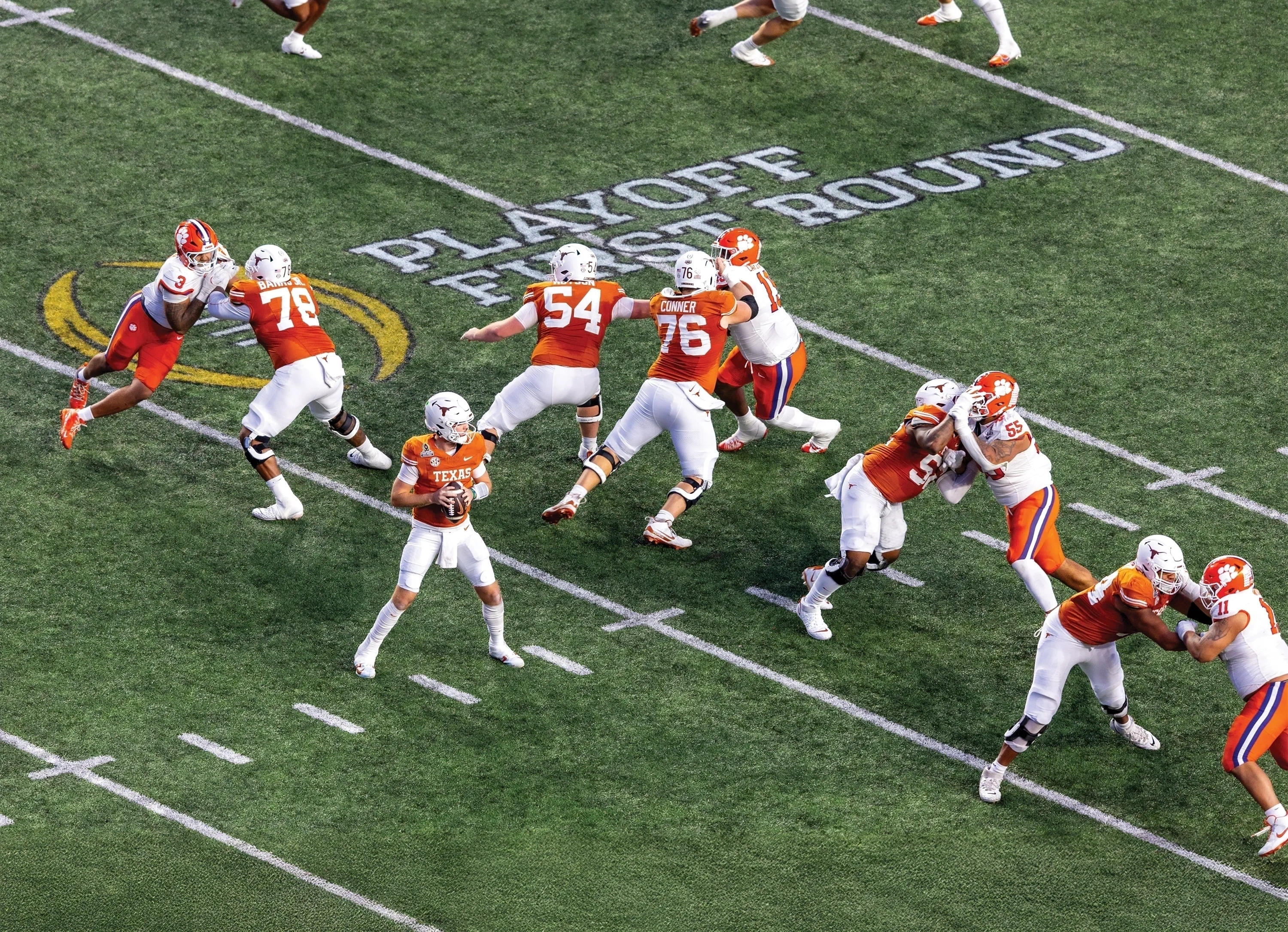 A Longhorn football player throws from behind the offensive line in orange uniform. The defense is in white.