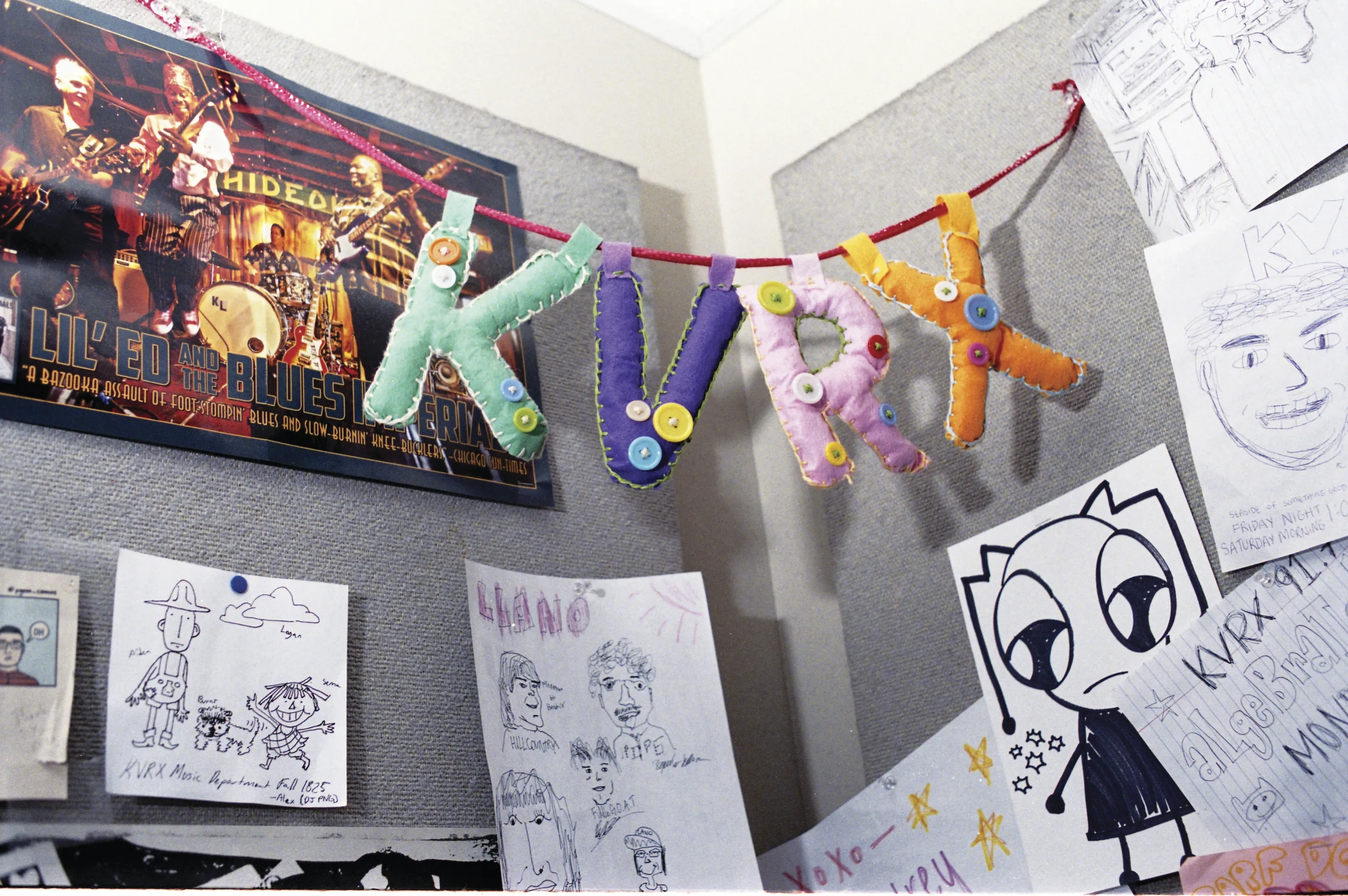 A felt-and-button garland hangs in the corner of a room that is adorned with cork boards covered in doodles.